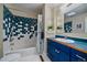 Retro bathroom with blue and white tile in shower, a skylight, and a blue vanity with a white sink at 5270 Tabor St, Arvada, CO 80002
