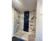 Modern walk-in shower with marble-look tile, unique blue accent tiles, and glass door at 9642 E Idaho Pl, Aurora, CO 80247