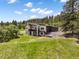 Beautiful view of a modern home surrounded by lush greenery, with an expansive yard, balcony and outdoor features at 3630 Mesa Verde Rd, Monument, CO 80132