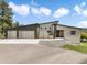 Modern home with a three-car garage, striking red door, and meticulously landscaped front yard with grey stucco and angular roofline at 3630 Mesa Verde Rd, Monument, CO 80132