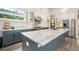 Bright, open kitchen featuring a large marble island, stainless steel appliances, and blue and white custom cabinetry at 3630 Mesa Verde Rd, Monument, CO 80132
