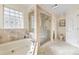 Bright bathroom featuring a soaking tub, glass enclosed shower, and tile flooring at 2400 S Clayton St, Denver, CO 80210