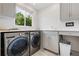 Well-organized laundry room with washer, dryer, storage cabinets, counter space, and window at 2400 S Clayton St, Denver, CO 80210