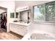 This bathroom boasts dual sinks, a large mirror, and a garden tub under a window at 4892 S Robb St, Littleton, CO 80127