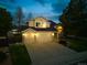 Inviting two-story home with a spacious three-car garage, manicured lawn, and warm exterior lighting at 4892 S Robb St, Littleton, CO 80127