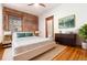 Bedroom with exposed brick wall, ceiling fan, hardwood floors, and staging at 1210 E Colfax Ave # 302, Denver, CO 80218