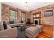 Charming living room with exposed brick walls, hardwood floors, a fireplace, and large windows at 1210 E Colfax Ave # 302, Denver, CO 80218