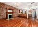 Spacious living room with exposed brick, hardwood floors, fireplace, and open kitchen access at 1210 E Colfax Ave # 302, Denver, CO 80218