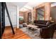 Living room with exposed brick, hardwood floors, leather sofa, and area rug at 1210 E Colfax Ave # 302, Denver, CO 80218