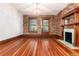 Empty living room showcasing hardwood floors, exposed brick, a fireplace, and natural light at 1210 E Colfax Ave # 302, Denver, CO 80218