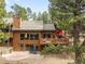 Charming home featuring a deck with outdoor seating, a stone patio, and surrounded by mature trees at 1943 Columbine Ct, Golden, CO 80401