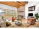 Cozy living room showcases a stone fireplace, wood ceiling, large windows, and stylish furnishings at 1943 Columbine Ct, Golden, CO 80401