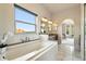 Bright and airy main bathroom featuring soaking tub with granite surround and window view at 10751 Fairway Vistas Ct, Littleton, CO 80125