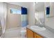 Bathroom featuring a white vanity, tub-shower combo with blue curtain, and a window for natural light at 1440 E 128Th Ct, Thornton, CO 80241
