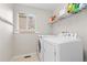 Bright laundry room featuring a white washer and dryer, shelving for storage, and hooks for hanging at 1440 E 128Th Ct, Thornton, CO 80241