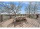 A dining table with chairs is placed on a wooden deck that overlooks a green field at 21166 E Euclid Dr, Centennial, CO 80016