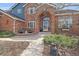 Close up of the front entrance featuring a brick archway, glass door, and well-manicured landscaping at 21166 E Euclid Dr, Centennial, CO 80016