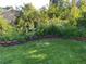 Lush backyard garden with brick edging, mature trees, bird bath and charming metal garden arch at 667 W Valleyview Ave, Littleton, CO 80120