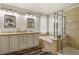 Well-lit bathroom featuring double vanity, soaking tub, and a separate shower with glass enclosure at 6471 S Potomac Ct, Englewood, CO 80111