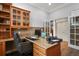 Office features a custom desk and drawers, wood floors, and custom cabinet with leaded glass doors at 6471 S Potomac Ct, Englewood, CO 80111