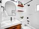 Modern bathroom with updated vanity, black hardware, decorative shelves, and a tiled shower and tub at 4201 Shoshone St, Denver, CO 80211
