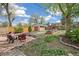 Lush backyard with a patio seating area, garden beds, a shed, and mature trees at 2170 W Warren Ave, Englewood, CO 80110