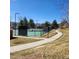 Outdoor tennis courts with paved walkway, trees, and mountain views in the background at 11710 Elk Head Range Rd, Littleton, CO 80127