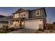 Charming two-story home showcasing a covered porch, two-car garage, stone accents, and manicured landscaping in the front yard at 17203 Birds Foot Ave, Parker, CO 80134