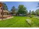 Well-maintained backyard with a tiered lawn, mature trees, and a rock water feature at 1324 Shadow Mountain Dr, Highlands Ranch, CO 80126