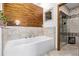 Luxurious bathroom featuring a modern soaking tub, wood accent wall, and glass-enclosed shower at 1324 Shadow Mountain Dr, Highlands Ranch, CO 80126