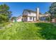 Rear exterior view showcasing the deck, chimney, windows, and lush lawn at 1324 Shadow Mountain Dr, Highlands Ranch, CO 80126