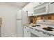 Cozy kitchen featuring all-white appliances and cabinets with tiled backsplash and flooring at 8060 Niwot Rd # 38, Niwot, CO 80503