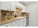 Bright kitchen with white cabinets, tan countertops, stainless steel dishwasher and stylish tiled backsplash at 8060 Niwot Rd # 38, Niwot, CO 80503