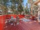 Outdoor deck featuring a hot tub and dining set with tall trees in the background at 28735 Little Big Horn Dr, Evergreen, CO 80439