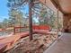 A covered wooden deck and a stone foundation of the home with trees in the background at 28735 Little Big Horn Dr, Evergreen, CO 80439