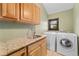 Well-equipped laundry room featuring a granite countertop, wood cabinets, and modern washer and dryer units at 1376 S Clayton St, Denver, CO 80210