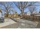 Spacious backyard with stone patio, gravel area, wooden fence, and mature trees at 1120 Quince St, Denver, CO 80220