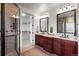 Bathroom featuring a double sink vanity, tile shower, and walk-in closet at 9586 Silent Hills Ln, Lone Tree, CO 80124