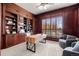 Elegant home office featuring wood paneled walls, built-in shelving, a modern desk and bright, natural light at 9586 Silent Hills Ln, Lone Tree, CO 80124