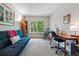 Bedroom with neutral carpet, a window with a leafy view, and a turquoise futon at 3571 S Kittredge St # C, Aurora, CO 80013