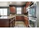Modern kitchen featuring stainless steel appliances, granite countertops, and dark wood cabinetry at 2015 E 167Th Ln, Thornton, CO 80602