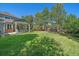 Expansive backyard with lush green lawn and mature trees leading to a covered patio at 10421 Kennemere Ln, Parker, CO 80134