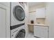 Bright laundry room features a modern washer/dryer, built-in shelving, sink, and white cabinets at 10421 Kennemere Ln, Parker, CO 80134