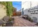 Cozy backyard with red stone patio, wicker seating, and mature vine growth at 1057 N Emerson St # B, Denver, CO 80218