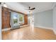 Sunlit bedroom with hardwood floors, exposed brick wall, ceiling fan, and large windows at 1057 N Emerson St # B, Denver, CO 80218