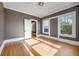 Sunlit bedroom with hardwood floors, two windows, gray accent wall, and white trim at 1057 N Emerson St # B, Denver, CO 80218