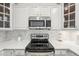 Bright kitchen with white cabinets, stainless steel appliances, and stylish herringbone backsplash at 2700 E Cherry Creek South Dr # 216, Denver, CO 80209