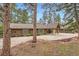 Exterior view of the house, featuring a stone facade, a large driveway, and mature trees at 4856 Cheyenne Dr, Larkspur, CO 80118