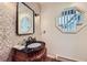 The powder room features unique wallpaper, a framed mirror, and a furniture-style vanity for added charm at 4856 Cheyenne Dr, Larkspur, CO 80118