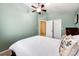 Bright bedroom with pale-green walls and white trim, ceiling fan, and white comforter with matching floral pillows at 9846 Spring Hill Ln, Highlands Ranch, CO 80129